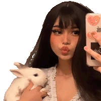 a girl is taking a selfie with her phone while holding a rabbit .