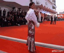 a woman stands on a red carpet in front of a crowd and a sign that says " gettyimages "