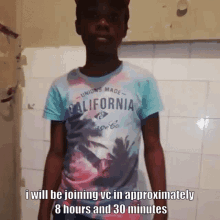 a boy wearing a california t-shirt is standing in front of a tiled wall