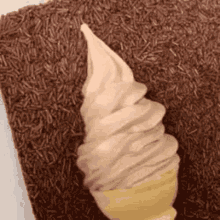 an ice cream cone is sitting on top of a pile of chocolate sprinkles on a table .