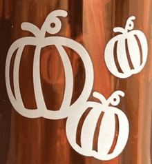 three white pumpkins are sitting next to each other on a wooden table .