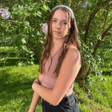 a woman wearing a headband and earrings stands in front of a tree