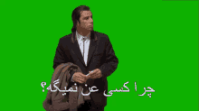 a man in a suit is standing in front of a green screen with arabic writing on it