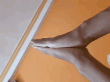 a person 's feet are against an orange wall with a white trim