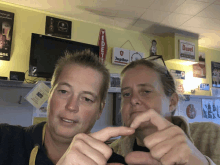 a man and a woman are making a heart shape with their fingers in front of a jupiler sign on the wall