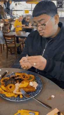 a man is sitting at a table with a plate of food and a packet of mayonnaise on the table