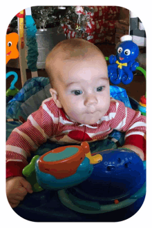 a baby is sitting in a bouncer with a toy octopus on it