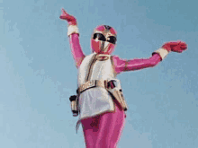 a woman in a pink superhero costume is standing in the air with her arms outstretched .