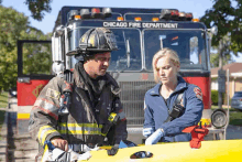 a fireman and a paramedic stand in front of a chicago fire department fire truck