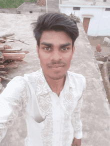 a young man in a white shirt takes a selfie with a cow in the background