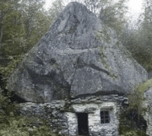 a small stone house with a large rock in the background .