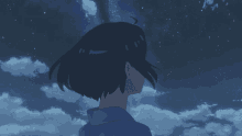 a girl in a blue shirt is looking up at the sky