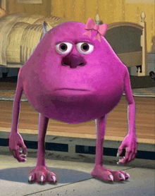 a purple monster with a pink bow on its head stands in a bedroom