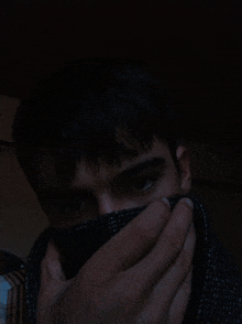 a man covering his face with a scarf in the dark