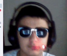 a man wearing headphones and sunglasses has a red light on his face