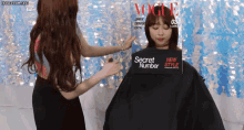 a woman is getting her hair cut with a vogue magazine cover