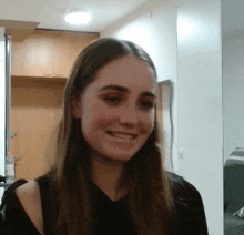 a young woman with long hair is smiling in a kitchen