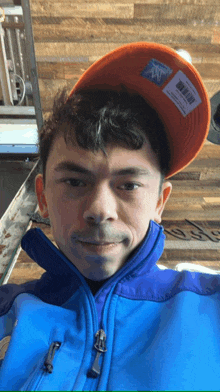 a man wearing a blue jacket and an orange hat with a tag that says ' columbia ' on it