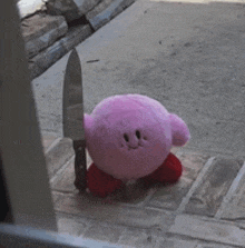 a pink kirby stuffed animal is holding a knife in its hand .