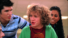 a boy with curly hair is wearing a green sweatshirt