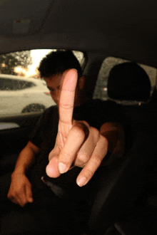 a man sitting in a car with his middle finger up