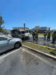 a group of firefighters are standing in front of a burning van