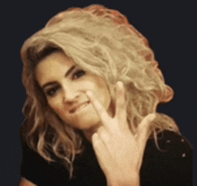 a woman with blonde hair is making a funny face while giving the middle finger .