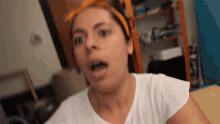 a woman wearing an orange headband is making a funny face .