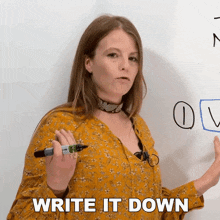 a woman holding a marker in front of a white board with the words " write it down " below her