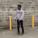 a young man in a white nike sweatshirt is dancing in front of a brick wall