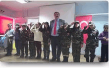 a man in a suit and tie is standing in front of a group of children in military uniforms .