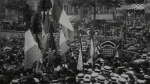 a black and white photo of a crowd of people with flags and a sign that says " who "