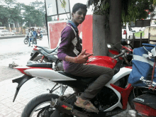 a young man sitting on a suzuki motorcycle giving a peace sign