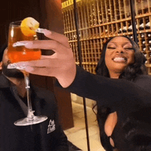 a woman holds up a glass of orange juice with a lemon slice on it