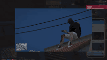 a video game screen shows a man sitting on a roof looking at his cell phone