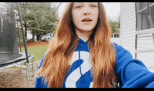 a girl wearing a blue hoodie with the number 2 on it takes a selfie