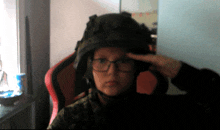 a person wearing glasses and a helmet salutes with their finger on their forehead