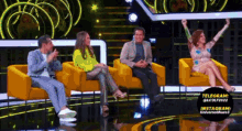 a group of people are sitting in yellow chairs on a stage with a telegram logo in the corner