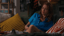 a woman in a blue shirt laying on a couch