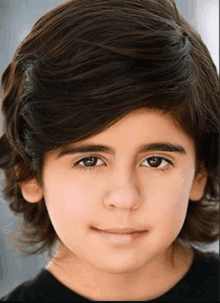 a young boy with long brown hair is smiling for the camera