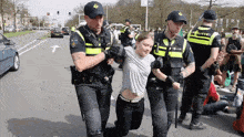 a woman is being escorted by a group of police officers one of whom has the word politie on his hat