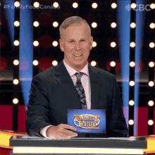 a man in a suit and tie stands in front of a podium with a sign that says family feud canada