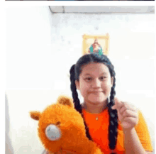 a young girl is holding a teddy bear and wearing a party hat .