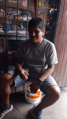 a man sitting on a bucket with a cup in his hand that says ' hp ' on it