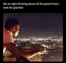 a man is standing on a balcony at night looking at the city lights .