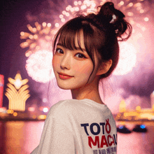 a woman wearing a toto macau t-shirt stands in front of a fireworks display