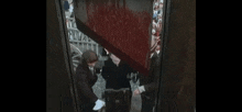 a group of people are standing next to each other in an elevator with blood coming out of the elevator door .