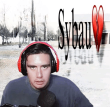 a man wearing red headphones stands in front of a sign that says sybau
