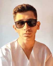 a man wearing sunglasses and a white shirt is looking at the camera