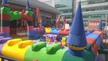 a colorful inflatable castle is in front of a building that says gbam